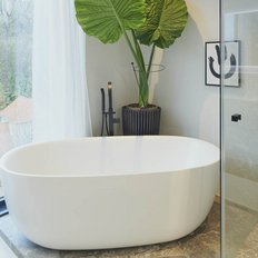 Ein modernes Badezimmer mit einer freistehenden Badewanne, großen Fenstern und Blick auf die Natur im Hintergrund.