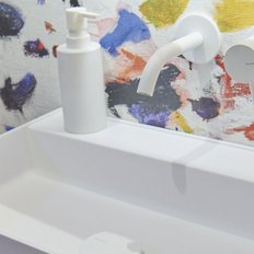 Ein modernes Waschbecken mit einem minimalistischen Design, umgeben von einer bunten, künstlerischen Wandgestaltung.