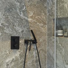 Eine moderne Dusche mit eleganten grauen Fliesen und einem minimalistischen Duschkopf, der an der Wand montiert ist.