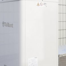 Die Vaillant-Wärmepumpe ist in einem hellen Außenbereich installiert, mit einem klaren Blick auf die strukturierten Wände im Hintergrund.