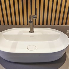 Ein elegantes Waschbecken aus weißem Keramik mit einem modernen Wasserhahn, umgeben von einer Holzvertäfelung.