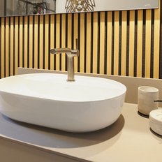 Ein elegantes Waschbecken aus weißem Keramik steht auf einer modernen, grauen Arbeitsplatte in einem stilvollen Badezimmer.