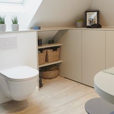 Ein modernes Badezimmer mit einer eleganten Toilette, einem Waschbecken und stilvollen Regalen voller Pflanzen und Handtüchern.