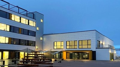 Moderne Architektur bei Dämmerung mit beleuchteten Fenstern Die Architektur des Gebäudes kombiniert Funktionalität und Ästhetik, um eine harmonische Umgebung zu schaffen.