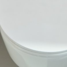 Ein modernes, weißes WC mit einem eleganten Design steht vor einer bunten Wandgestaltung, die lebendige Farben zeigt.