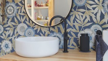Ein elegantes Waschbecken aus weißem Keramik steht auf einem Holzregal, umgeben von einer blauen, floral gemusterten Wand.
