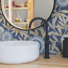 Ein elegantes Waschbecken aus weißem Keramik steht auf einem Holzregal, umgeben von einer blauen, floral gemusterten Wand.