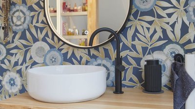 Ein elegantes Waschbecken aus weißem Keramik steht auf einem Holzregal, umgeben von einer blauen, floral gemusterten Wand.