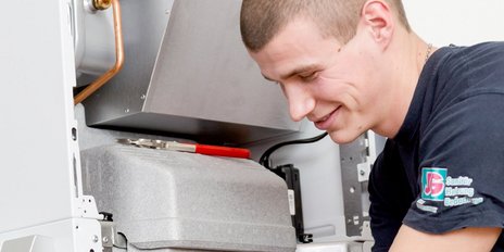 Der Techniker überprüft sorgfältig die Innenteile eines Geräts, während er mit einem Schraubenschlüssel arbeitet.
