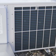 Die Klimaanlage hat ein weißes Gehäuse mit einem Gitter aus blauen Lamellen, das für die Luftzirkulation sorgt.