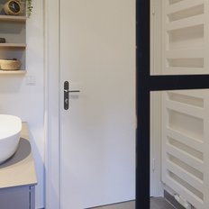 Ein modernes Badezimmer mit einem eleganten, ovalen Waschbecken und einer stilvollen Holzverkleidung an der Wand.