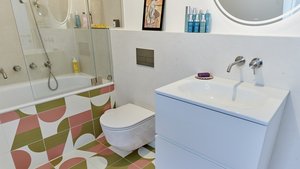 Ein modernes Badezimmer mit einer Badewanne, einer Dusche und bunten, geometrischen Fliesen, die einen frischen Look verleihen.