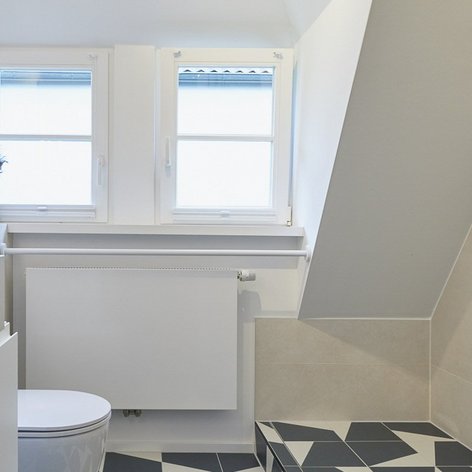 Ein modernes Badezimmer mit einem eleganten Waschbecken, weißen Wänden und großen Fenstern, die viel Licht hereinlassen.