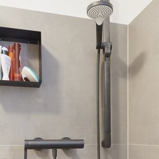 Eine moderne Dusche mit grauen Wänden, ausgestattet mit einer eleganten Handbrause und einem praktischen Regal für Pflegeprodukte.
