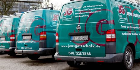 Vier grüne Lieferwagen mit dem Logo von Jens Gottschalk stehen auf einem Parkplatz, bereit für den nächsten Einsatz.