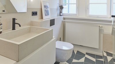 Ein modernes Badezimmer mit einem eleganten Waschbecken aus Beton und einem stilvollen schwarzen Wasserhahn.
