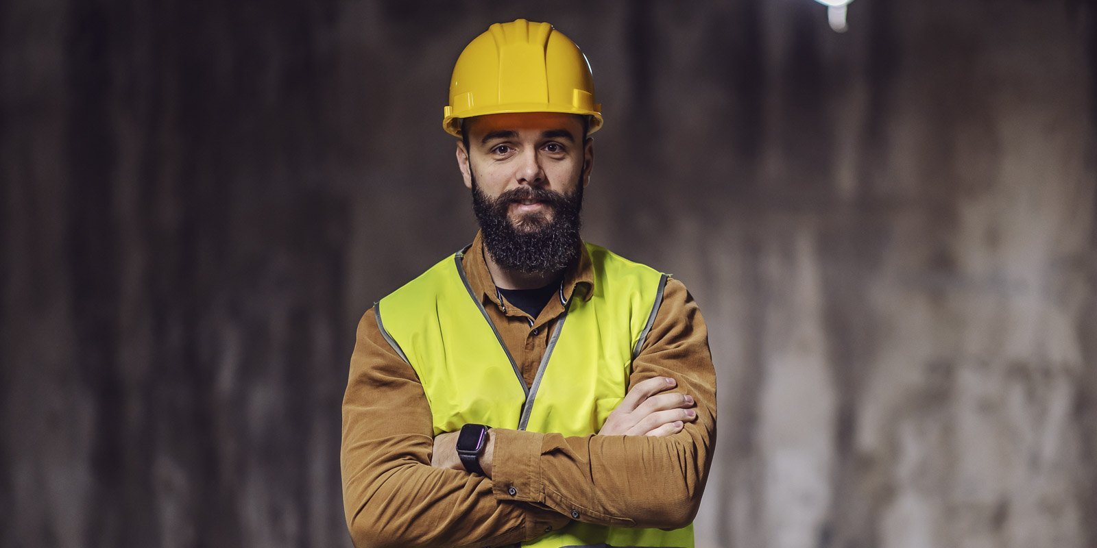 Ein Bauhelfer mit verschränkten Armen