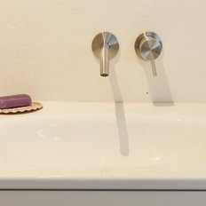 Das Bild zeigt ein minimalistisches Badezimmer mit einem weißen Waschbecken und einem stilvollen Seifenstück in lila.