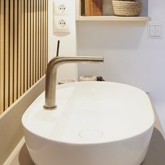 Ein elegantes Waschbecken mit einem modernen Wasserhahn vor einer stilvollen Holzlattenwand in einem hellen Raum.