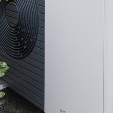 Eine moderne Wärmepumpe steht zwischen grünen Pflanzen, die frisches Leben und eine umweltfreundliche Technologie symbolisieren.