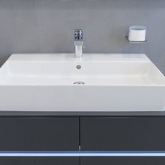 Ein modernes Waschbecken aus weißem Keramik, das auf einem eleganten grauen Unterschrank platziert ist.