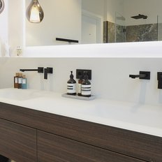 Ein modernes Badezimmer mit einem eleganten Holzwaschtisch und stilvollen Seifenspendern auf der Ablage.