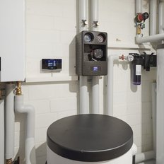 Ein moderner Heizkessel mit digitalen Anzeigen und zahlreichen Rohren in einem hellen, funktionalen Raum.