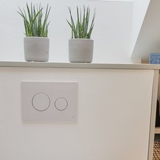 Ein stilvoller Raum mit einem schwarzen Origami-Hase, zwei Pflanzen in Töpfen und einem modernen Lichtschalter an der Wand.