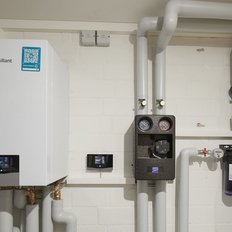 Eine moderne Heizungsanlage mit einem weißen Vaillant-Gerät und zahlreichen Rohren, die an der Wand montiert sind.