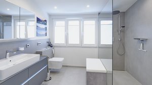Ein modernes Badezimmer mit einem großen Spiegel, einer eleganten Dusche und viel natürlichem Licht durch die Fenster.