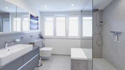 Ein modernes Badezimmer mit einem großen Spiegel, einer eleganten Dusche und viel natürlichem Licht durch die Fenster.