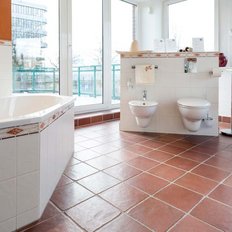 Das Badezimmer zeigt eine stilvolle Badewanne, zwei Toiletten und Pflanzen auf der Fensterbank, die eine frische Atmosphäre schaffen.