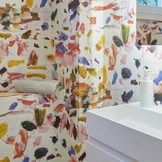 Ein modernes Badezimmer mit einer weißen Waschbeckenanlage vor einer bunten, künstlerisch gestalteten Wand.